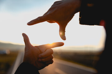 Hands in the shape of picture frame against the sunset