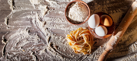 Portion of homemade noodles on floured kitchen table flat lay cooking background with copy-space
