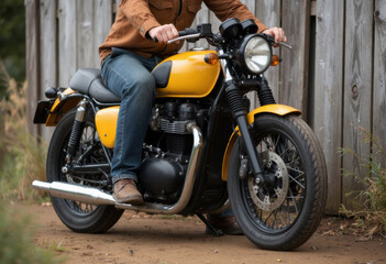 A stylish yellow motorcycle parked on a dirt road beside a wooden fence