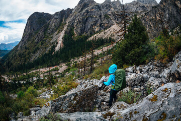Naklejka premium Backpacking woman climbing up on steep cliff edge at high altitude mountains top