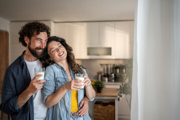 Happy couple drinking milk and embracing in kitchen