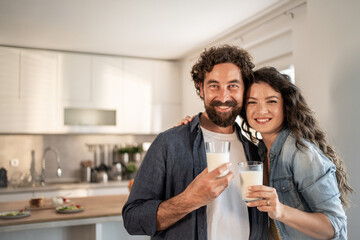 Happy couple drinking milk in modern kitchen: promoting healthy lifestyle
