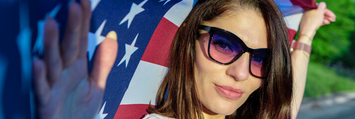 Beautiful woman with USA flag outdoor. Young woman standing on street holding usa flag.
