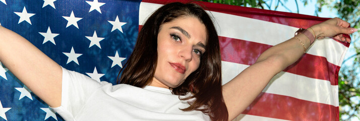 Beautiful woman with USA flag outdoor. Young woman standing on street holding usa flag.
