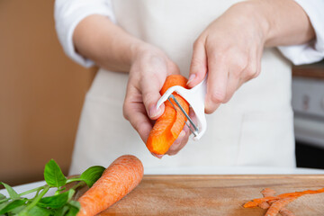 Person peeling carrot with vegetable peeler
