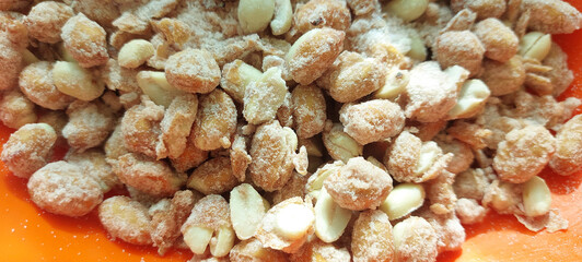 Sugar coated peanuts in the orange plate. Close-up.