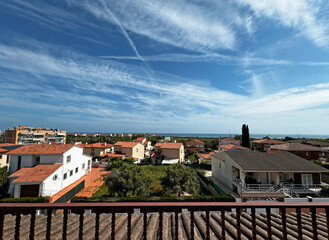 A view of a village off the coast of Spain with the sky covered in airplane tracks
