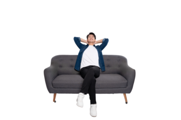 Full body image of young Asian man using phone sitting on sofa on PNG background	