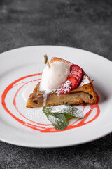 A beautifully crafted dessert showcases layers of flaky pastry topped with creamy ice cream and vibrant strawberries, elegantly served at a fine dining establishment