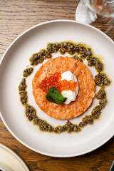 A vibrant dish showcases an exquisite blend of flavors, featuring a rich base topped with dollops of cream, luxurious fish roe, and fresh herbs, all artfully arranged on a stylish plate