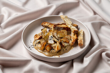 Delicate presentation of a gourmet dish showcases tender roasted vegetables paired with a rich, creamy sauce. Served elegantly on soft fabric, this culinary delight captivates the senses