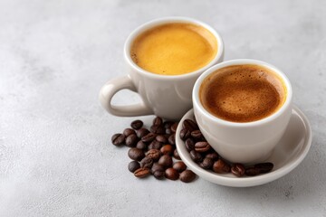 Fototapeta premium Espresso Duo: Creamy and Dark Coffee Cups with Roasted Beans