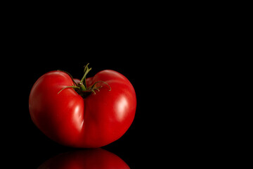 One pink tomato, macro, isolated on black background.