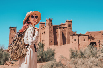 Tourist with backpack and hat enjoying view of fortified city of Ait Benhaddou, a world heritage site in Morocco