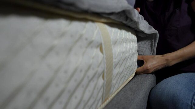 Close-up of a person placing a stack of Russian Rubble bills under a mattress
