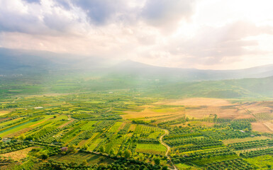 Obraz premium sunset valley landscape with green trees and gardens among beautiful mountains with colorful cloudy sky on background