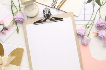 Wedding rings and flowers on white wooden background with space for inscription