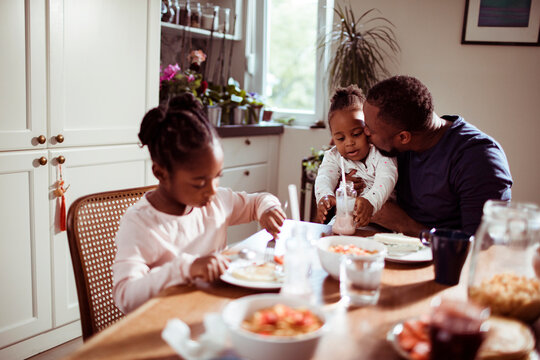Single father having breakfast with his two young daughters at home