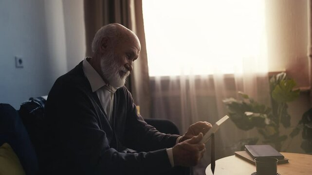 Lonely elderly man holding framed photo, missing his family, nostalgic moment