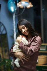 Fototapeta premium Young mom holding in her hands infant boy at home