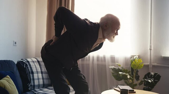 Sad senior man with lower back pain while standing up, possible radiculitis