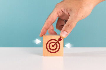 Concept of purposeful movement towards the goal. A man put down wooden block with target symbol...