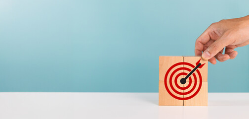 Business success, successful goals, reach goals. A man put down wooden blocks with target icon...