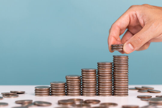 Concept for investment, Invest, profit, finance and saving money. A man put down coins stack step growing growth indicates saving money - Powered by Adobe
