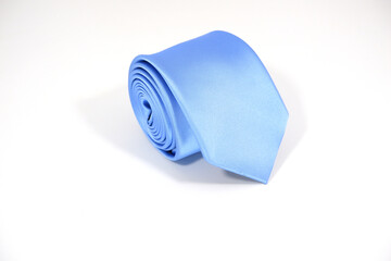 A plain blue tie rolled isolated on white background closeup view 