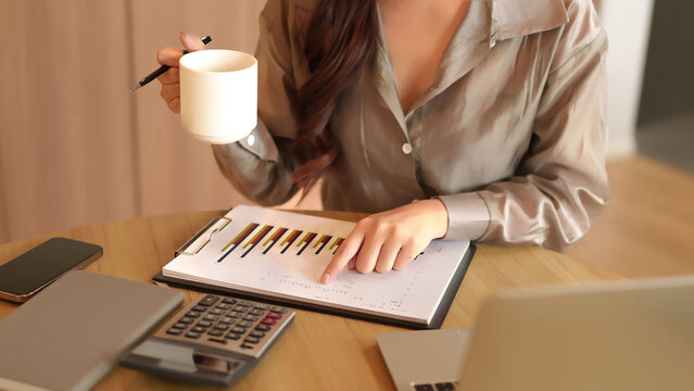 Asian Business Woman Analyzing Charts and Graphs at Desk