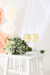 Glasses of champagne and wedding bouquet on table indoors