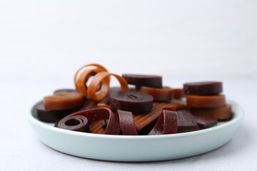 Tasty fruit leather rolls on white table, closeup. Space for text
