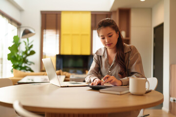 Asian Adult Woman Calculates Finance Working At Home With Laptop