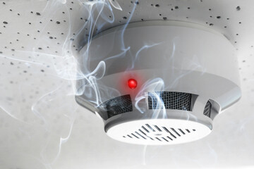 Fire alarm system. Detector on ceiling triggered by smoke