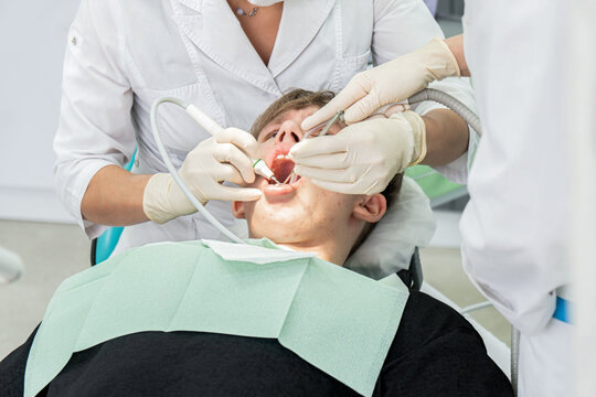 Teenager undergoes dental procedures in a bright clinic with professionals attending to oral health needs
