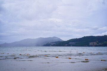 Calm Beach Scene with Mountains and Overcast Sky..