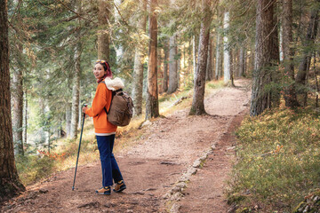 Young hiker walking in a forest path during autumn, enjoying the sunlight