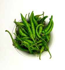 Green hot chili pepper in bowl isolated on white background. Perfect for design element, spicy food concept or any commercial usages. Green chili closeup top view. High resolution image.