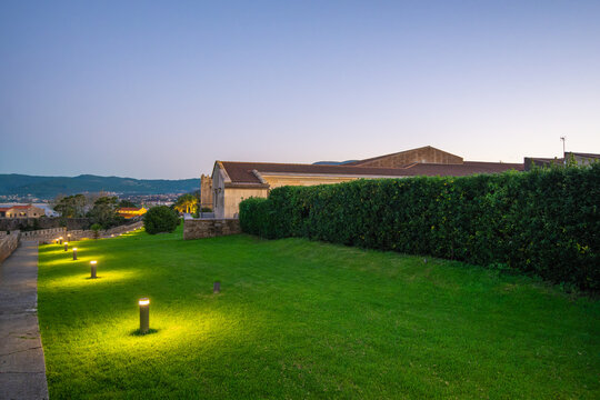 The elegant Parador of Baiona, a former castle with a rich history, glows under garden lights at dusk in Spain.