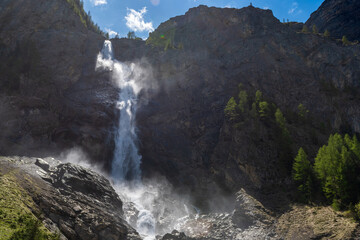 A roaring alpine waterfall crashes over cliffs surrounded by spring bloom. This is Engstligenfälle...