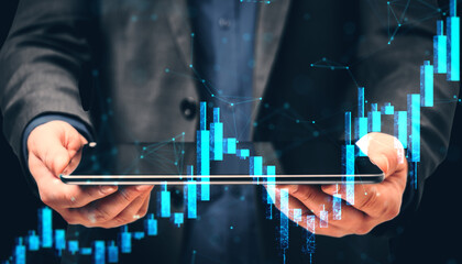 Businessman holding tablet with digital stock market chart interface and glowing financial data bars over dark background for investment analysis.