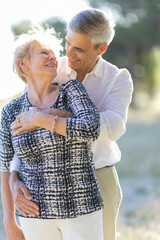 Naklejka premium Happy senior couple embracing in summer park