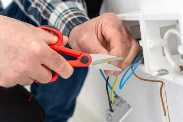 Electrician worker at work with scissors prepares the electrical cables of an electrical system. Construction industry.