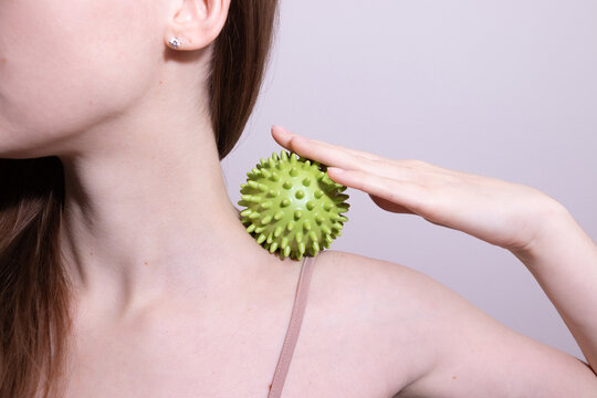 Woman using  massage ball to relieve chronic neck, shoulder tension. Myofascial release therapy at home.
