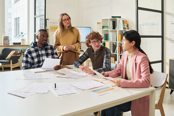 Group of diverse individuals engaged in studying foreign languages in modern classroom environment,...