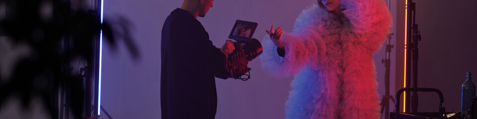 Header image of studio filming setup with woman performing in costume and cameraman recording during video shoot