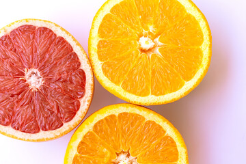 Close-up of juicy orange and grapefruit halves on a soft pink surface, showcasing bright citrus...