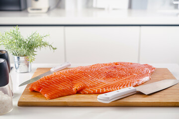 Close up one fresh raw salmon fish fillet on cutting board, with kitchen knife, herbs and salt