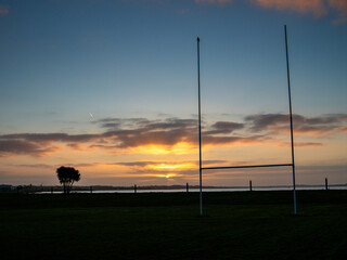 Silhouette of a tall goal posts in a field against dramatic sunrise sky. National sport of Ireland...
