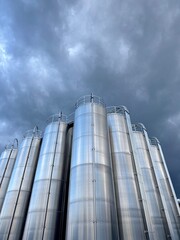 Large stack of silvery tanks with a cloudy sky in the background